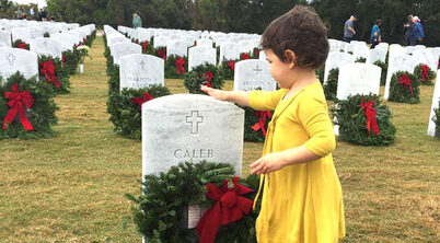 Child touching a tombstone adding a wreath.