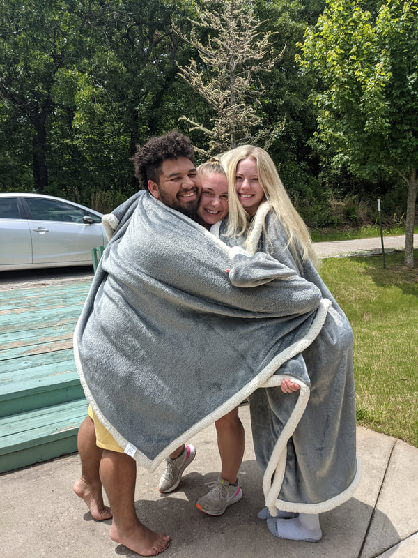 Survivors embracing in a huge hug wrapped in blankets and big smiles.